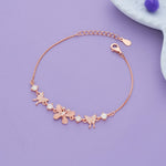 Rose gold silver bracelet with butterfly and flower charms on a purple background