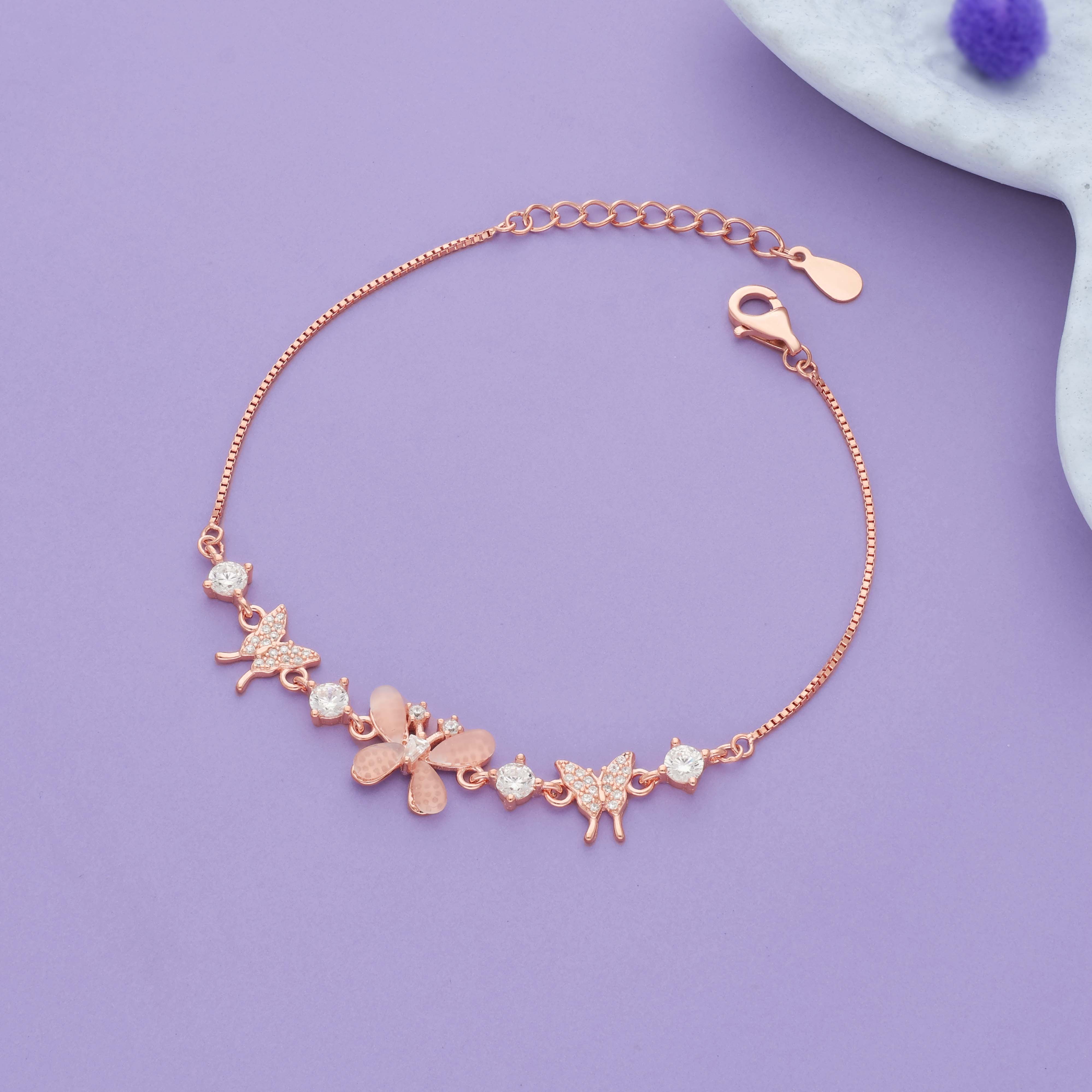 Rose gold silver bracelet with butterfly and flower charms on a purple background